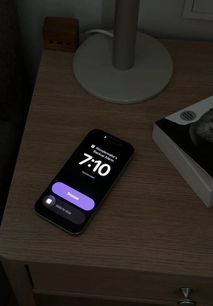 Alarma de respaldo de WonderWake en la pantalla bloqueada de un iPhone con las opciones posponer y deslizar para detener